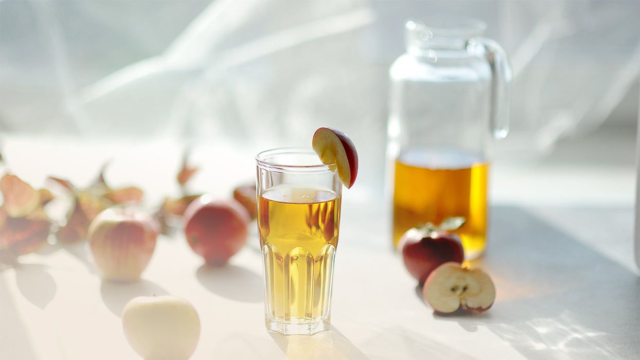 Aepfel Glas Glaskaraffe Apfelcidre helles Licht weisser Hintergrund